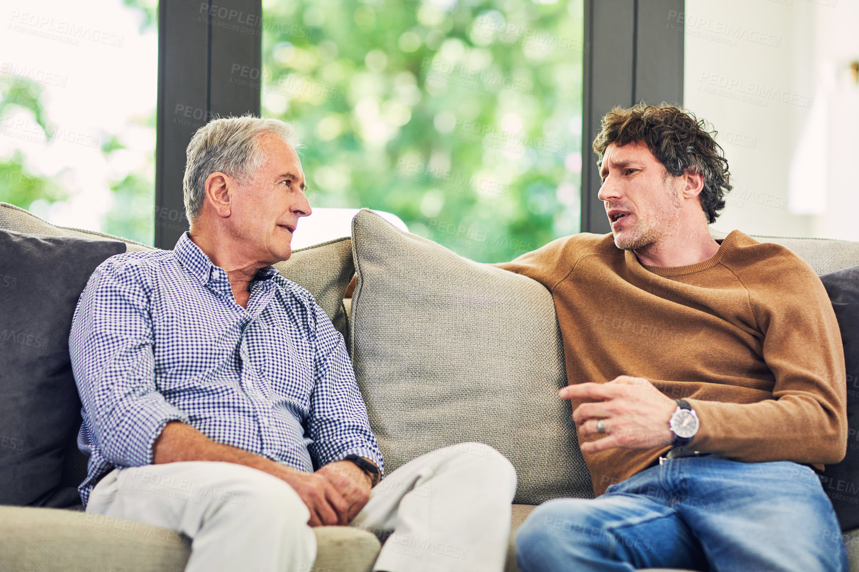 Buy stock photo Shot of a mature man and his elderly father sitting on the sofa at home and chatting