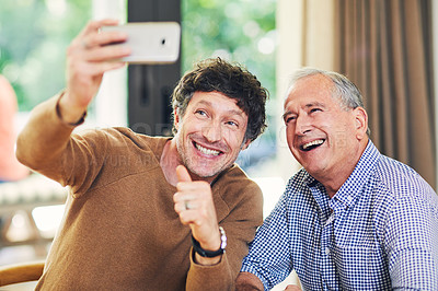 Buy stock photo Shot of a mature man and his elderly father taking selfies together at home