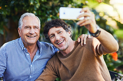 Buy stock photo Shot of a mature man and his elderly father taking selfies together in a garden