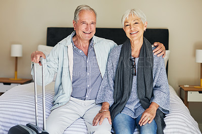 Buy stock photo Shot of a happy senior couple sitting on a bed in their hotel room