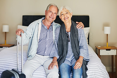 Buy stock photo Shot of a happy senior couple sitting on a bed in their hotel room