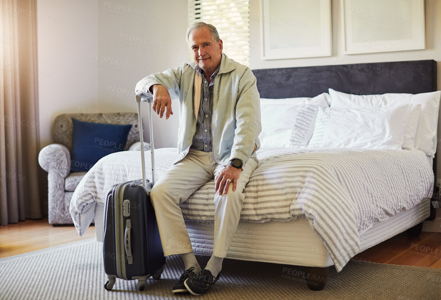 Buy stock photo Shot of a happy senior man sitting on a bed in his hotel room