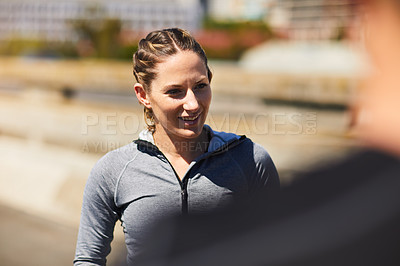 Buy stock photo Shot of a sporty young woman talking to her someone while exercising outside