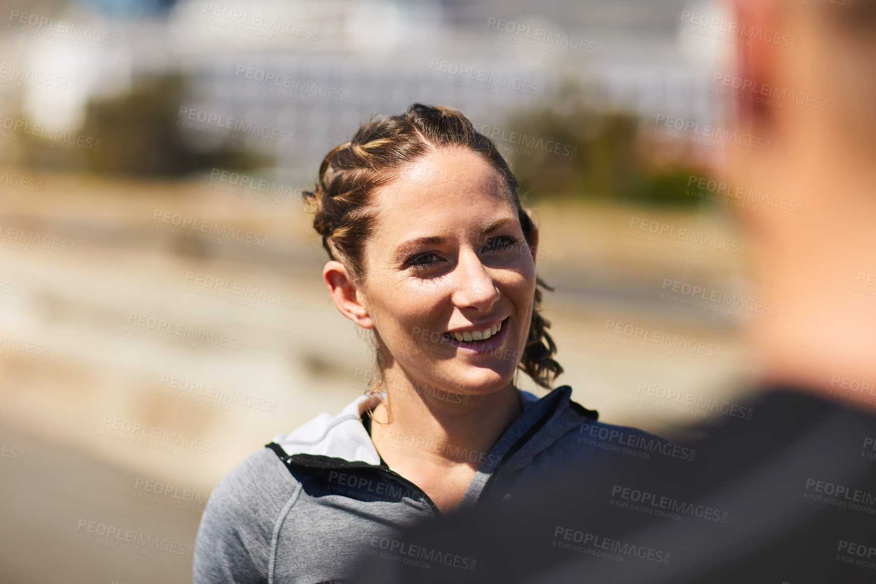 Buy stock photo Shot of a sporty young woman talking to her someone while exercising outside