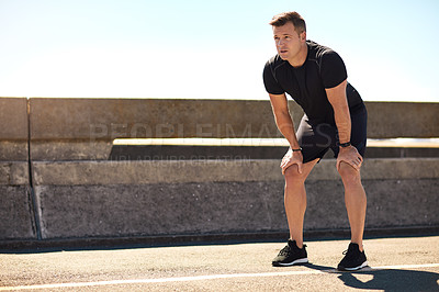 Buy stock photo Shot of a sporty young man out for a run on a bridge in the city
