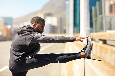 Buy stock photo Shot of a sporty young man stretching before his run
