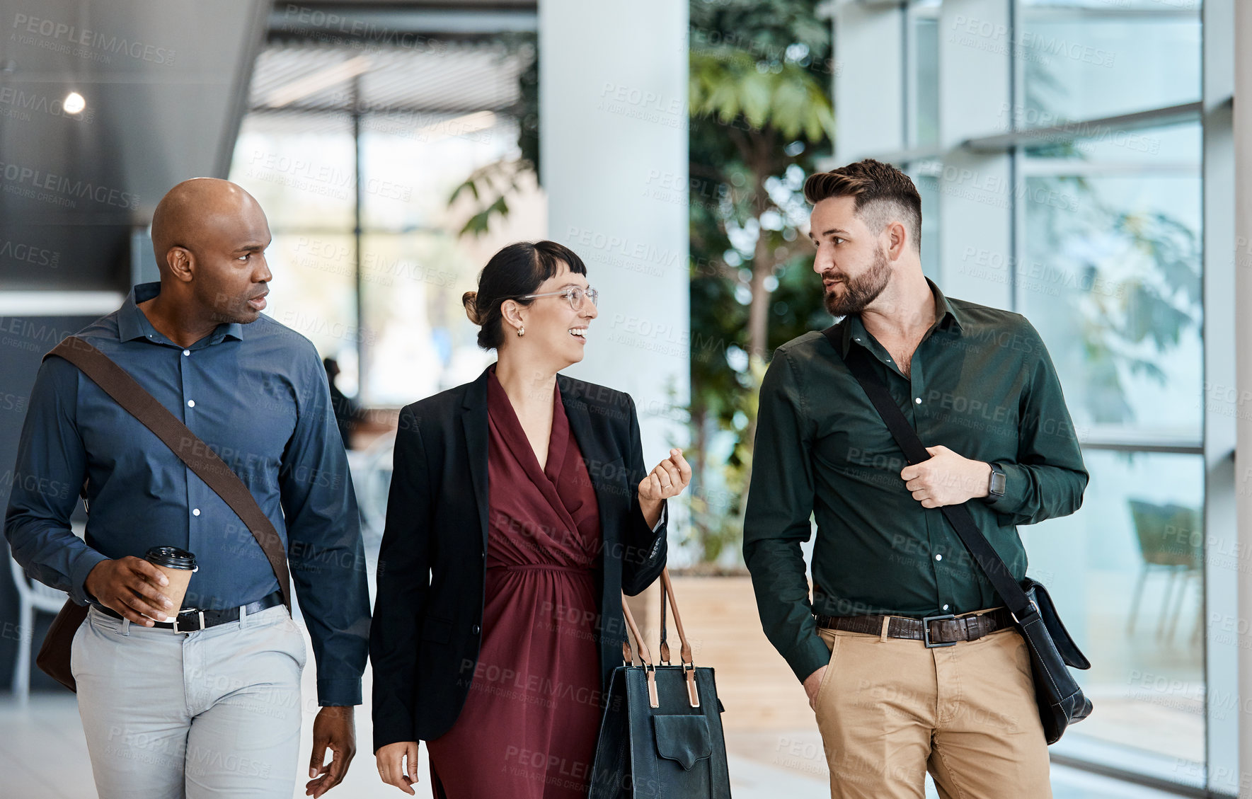 Buy stock photo Cropped shot of three business colleagues talking while walking through their office