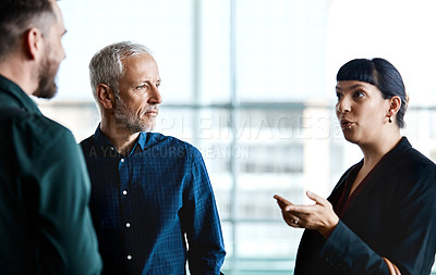 Buy stock photo Cropped shot of three business colleagues talking while standing in their office