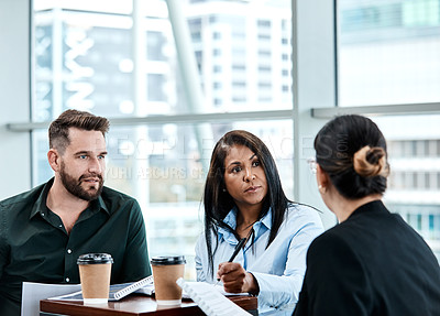 Buy stock photo Cropped shot of three business colleagues having a discussion while sitting in their office