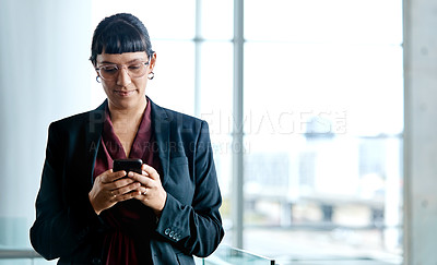 Buy stock photo Cropped shot of an attractive businesswoman texting while standing in her office
