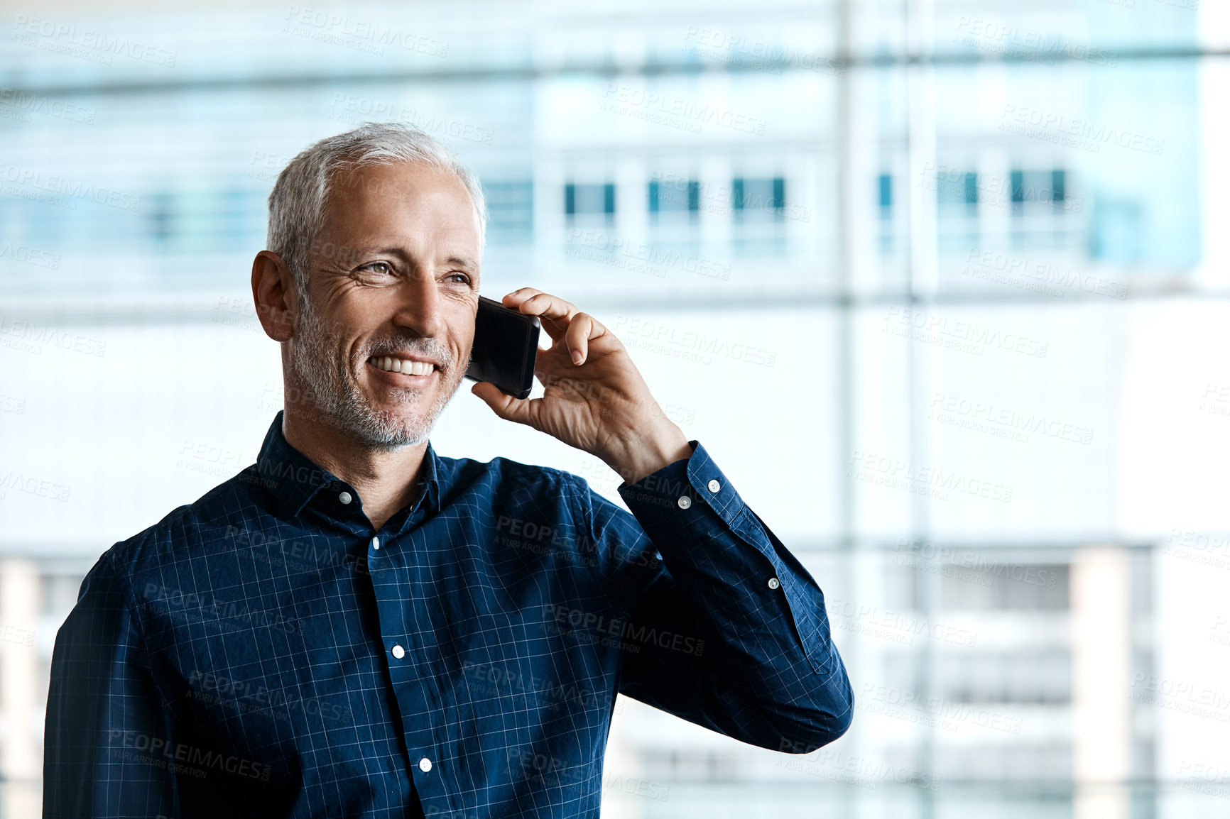 Buy stock photo Cropped shot of a handsome businessman making a phonecall while standing in his office