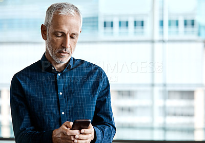 Buy stock photo Cropped shot of a handsome businessman texting while standing in his office