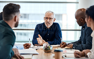 Buy stock photo Shot of a mature businessman discussing ideas with colleagues during a meeting at work