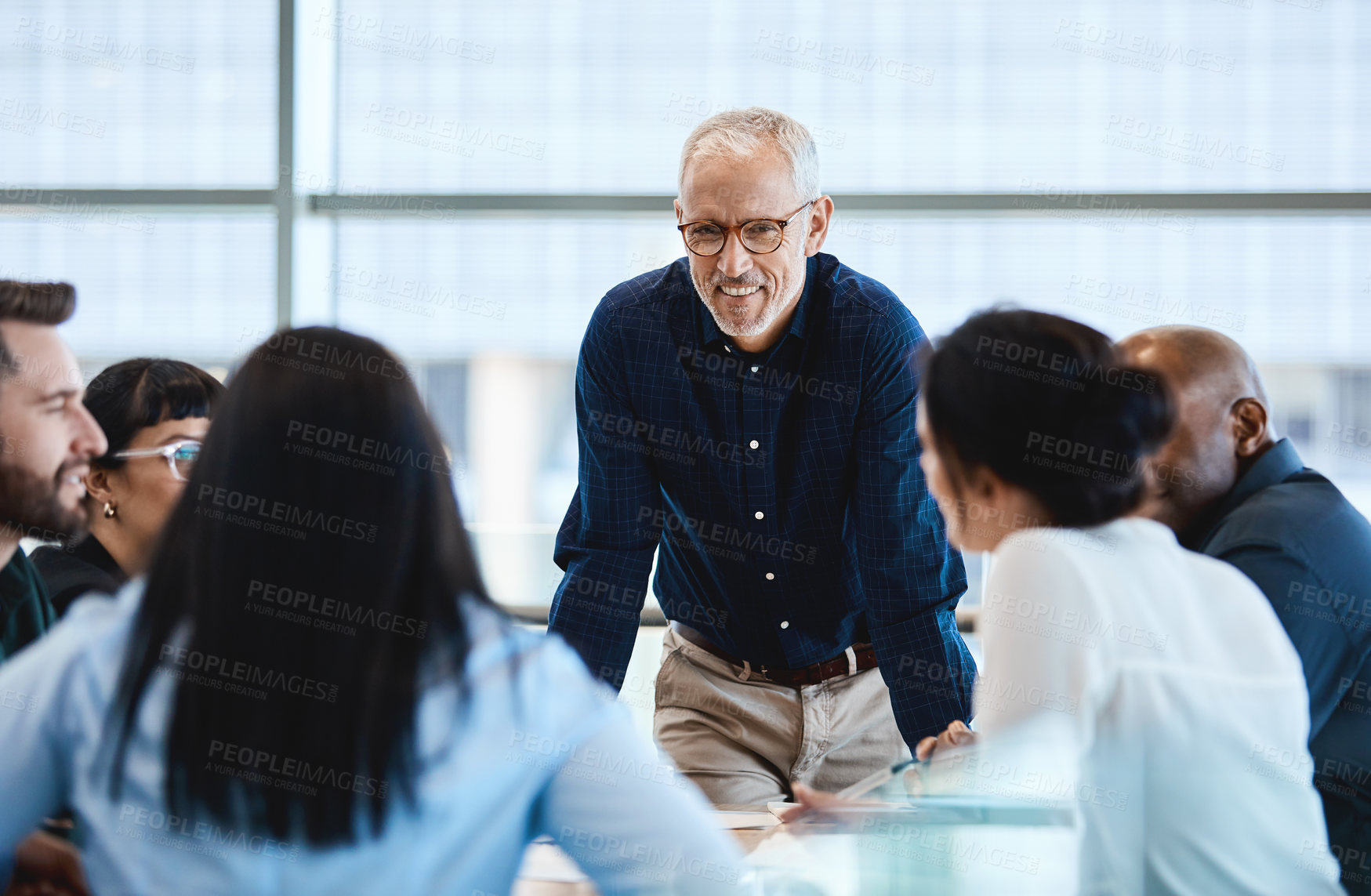 Buy stock photo Shot of a mature businessman smiling during a meeting with colleagues at work