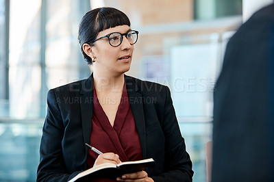 Buy stock photo Shot of an attractive young businesswoman taking down notes during a meeting with colleagues at work