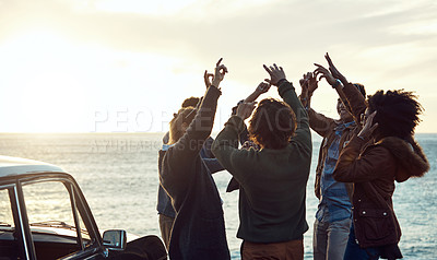 Buy stock photo Cropped shot of a diverse group of young friends standing together and dancing on the beach while road tripping