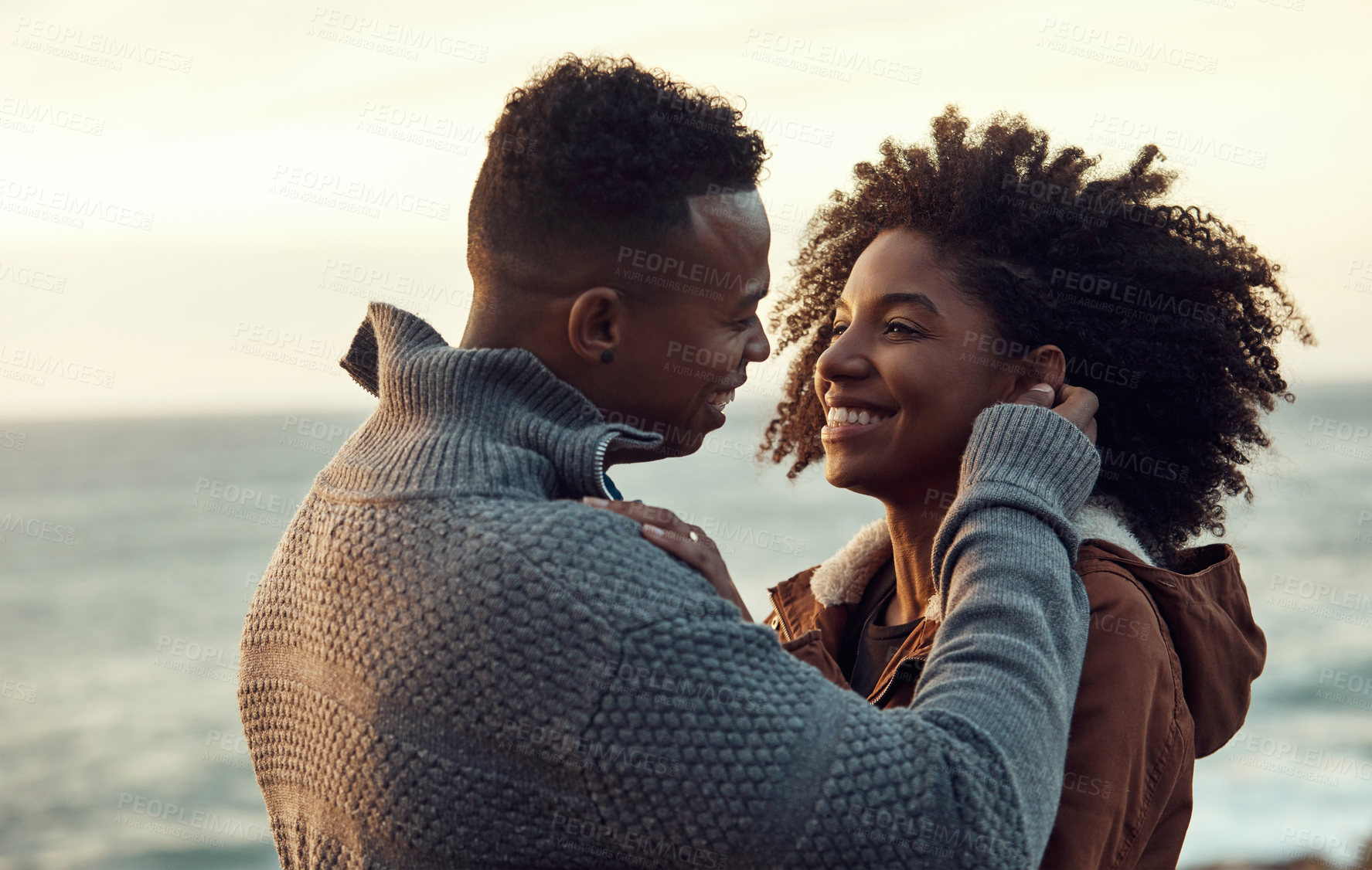 Buy stock photo Cropped shot of an affectionate young couple holding each other while standing on the beach during a road trip