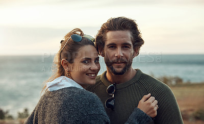 Buy stock photo Cropped portrait of an affectionate and happy young couple holding each other closely at the beach during a road trip