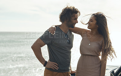 Buy stock photo Cropped shot of an affectionate young couple holding each other and standing together on the beach during a road trip