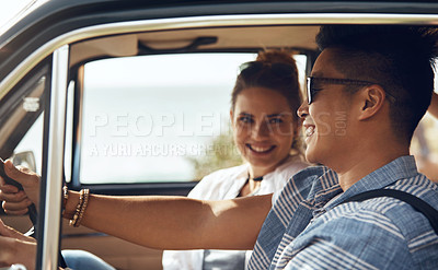 Buy stock photo Cropped shot of a happy and affectionate young couple sitting in a car and driving during the day