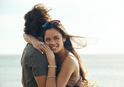 Buy stock photo Cropped portrait of an affectionate young couple hugging each other while standing on the beach during a road trip