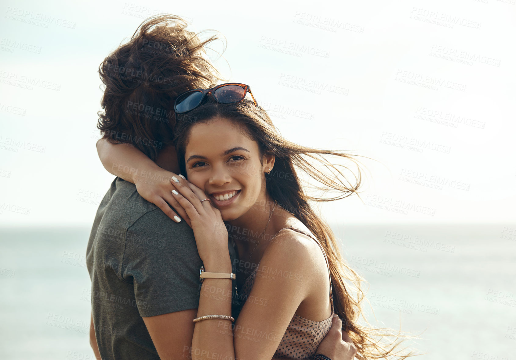 Buy stock photo Cropped portrait of an affectionate young couple hugging each other while standing on the beach during a road trip