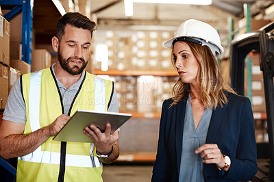 Buy stock photo Cropped shot of an attractive young businesswoman walking through a warehouse with a male worker