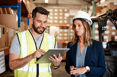 Buy stock photo Cropped shot of an attractive young businesswoman walking through a warehouse with a male worker