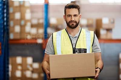 Buy stock photo Cropped portrait of a handsome young male warehouse worker carrying a box