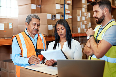 Buy stock photo Cropped shot of three warehouse workers checking on distribution logistics