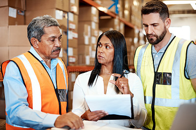 Buy stock photo Cropped shot of three warehouse workers checking on distribution logistics