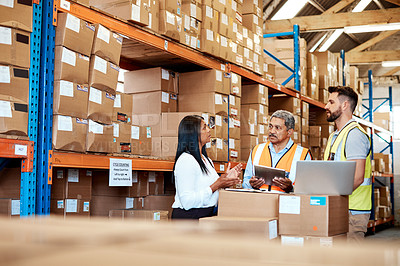 Buy stock photo Cropped shot of three warehouse workers checking on distribution logistics