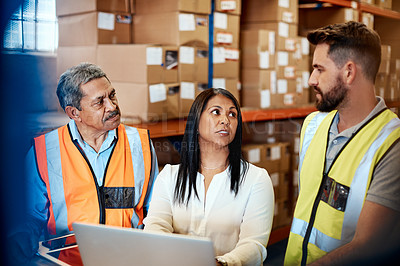 Buy stock photo Cropped shot of three warehouse workers checking on distribution logistics