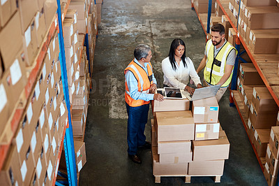 Buy stock photo High angle shot of three warehouse workers checking on distribution logistics