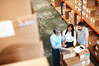 Buy stock photo High angle shot of three warehouse workers checking on distribution logistics