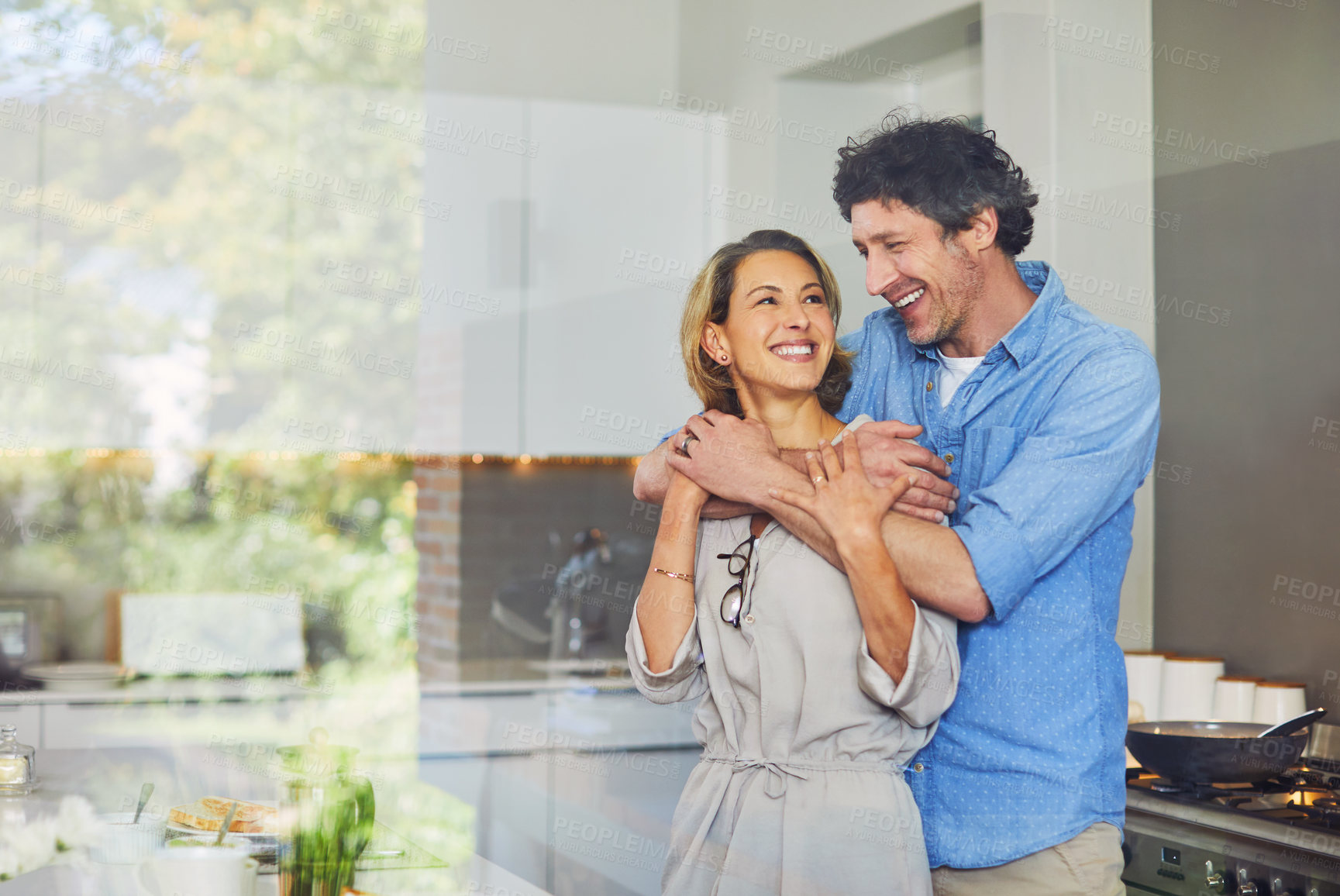 Buy stock photo Shot of a mature couple hugging in the kitchen at home