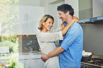 Buy stock photo Shot of a mature couple hugging in the kitchen at home