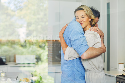 Buy stock photo Shot of a mature couple hugging in the kitchen at home