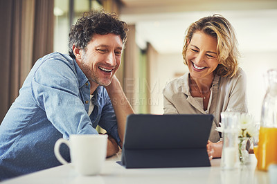 Buy stock photo Shot of a mature couple using a digital tablet while having breakfast at home