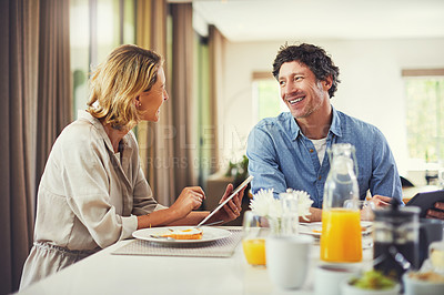 Buy stock photo Shot of a mature couple using a digital tablet while having breakfast at home