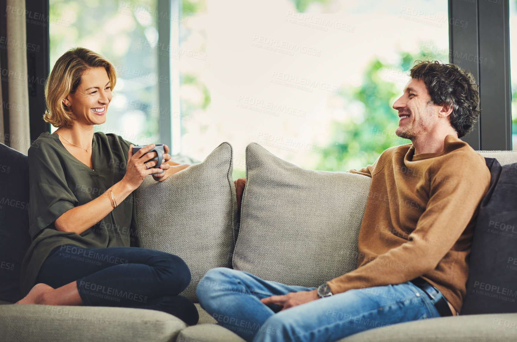 Buy stock photo Couple, happiness and relax on sofa with conversation, bonding and quality time at home with coffee. Mature, people laughing or chat in living room, commitment or together with relationship and break
