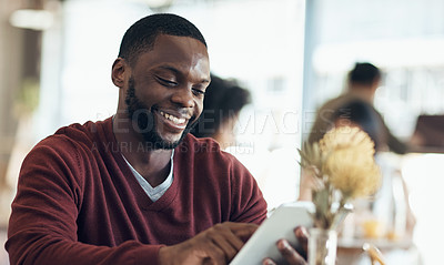 Buy stock photo Cropped shot of a handsome young businessman sitting in a cafe and using a tablet