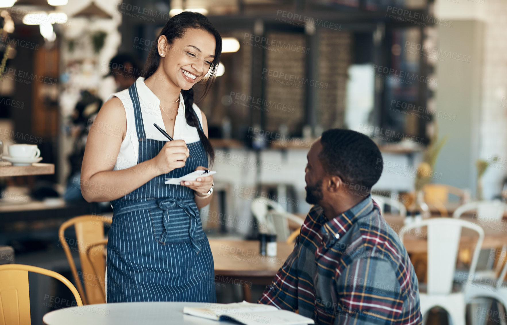 Buy stock photo Cropped shot of an attractive young waitress taking down an order for a male customer in the cafe