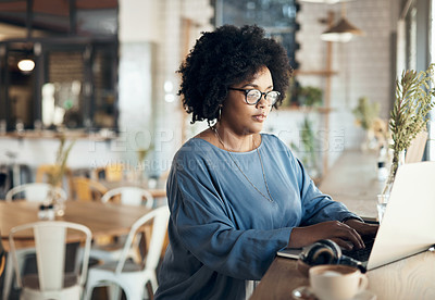 Buy stock photo Cropped shot of an attractive young businesswoman sitting alone and working on her laptop in a cafe
