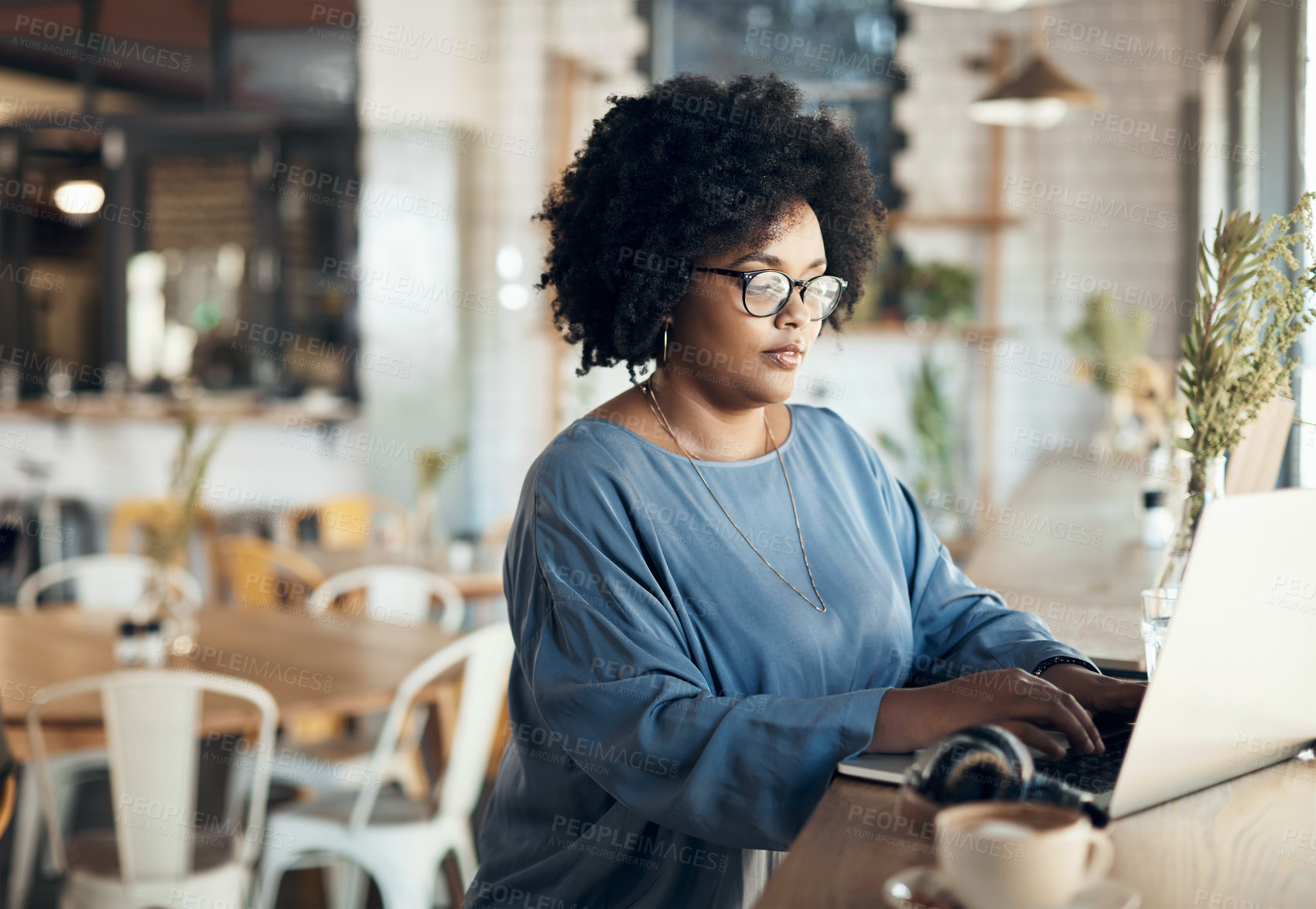 Buy stock photo Cropped shot of an attractive young businesswoman sitting alone and working on her laptop in a cafe