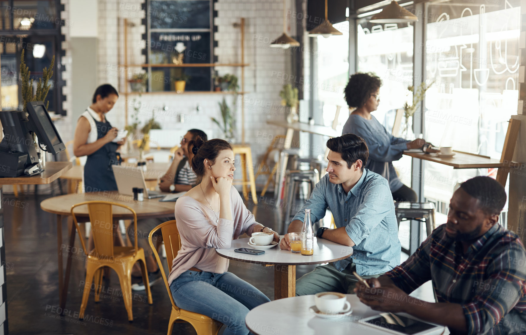 Buy stock photo Cropped shot of a young couple sitting together during a coffee date in a busy cafe