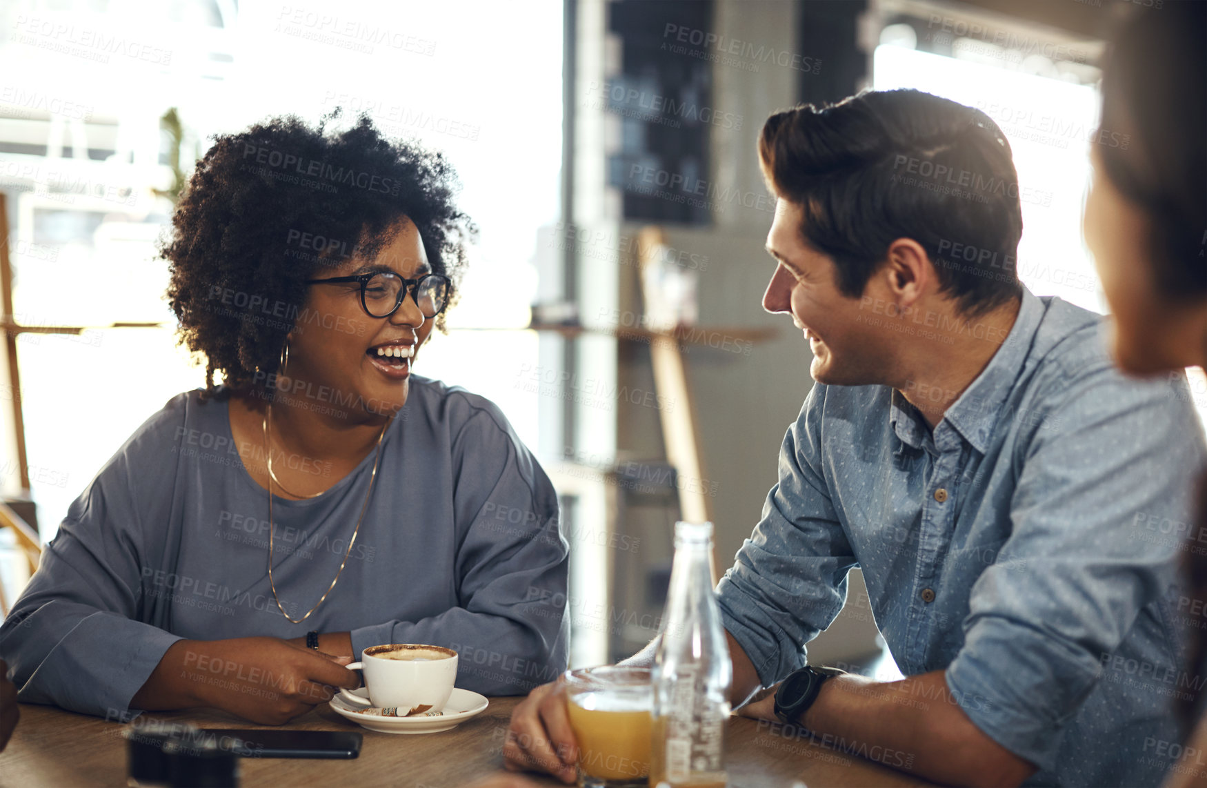 Buy stock photo Cropped shot of an attractive young woman sitting and enjoying a cup of coffee with her friends in a cafe
