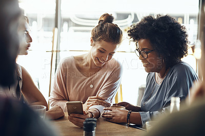 Buy stock photo Cropped shot of a diverse group of friends sitting together and using a cellphone while bonding in a coffee shop