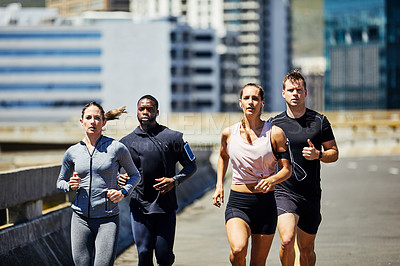 Buy stock photo Shot of a group of sporty young people out for a run in the city