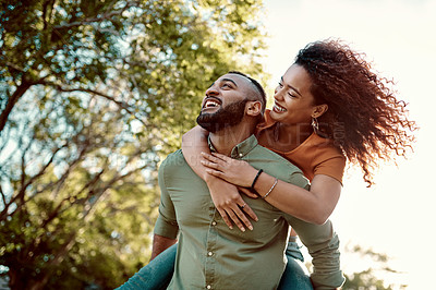Buy stock photo Shot of a young man giving his girlfriend a piggyback ride outdoors